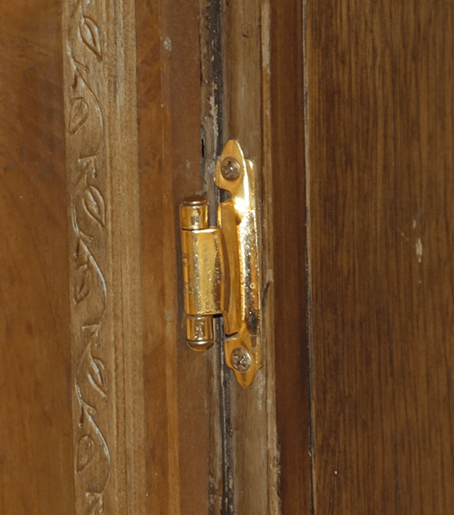 Close-up of a small cabinet hinge.